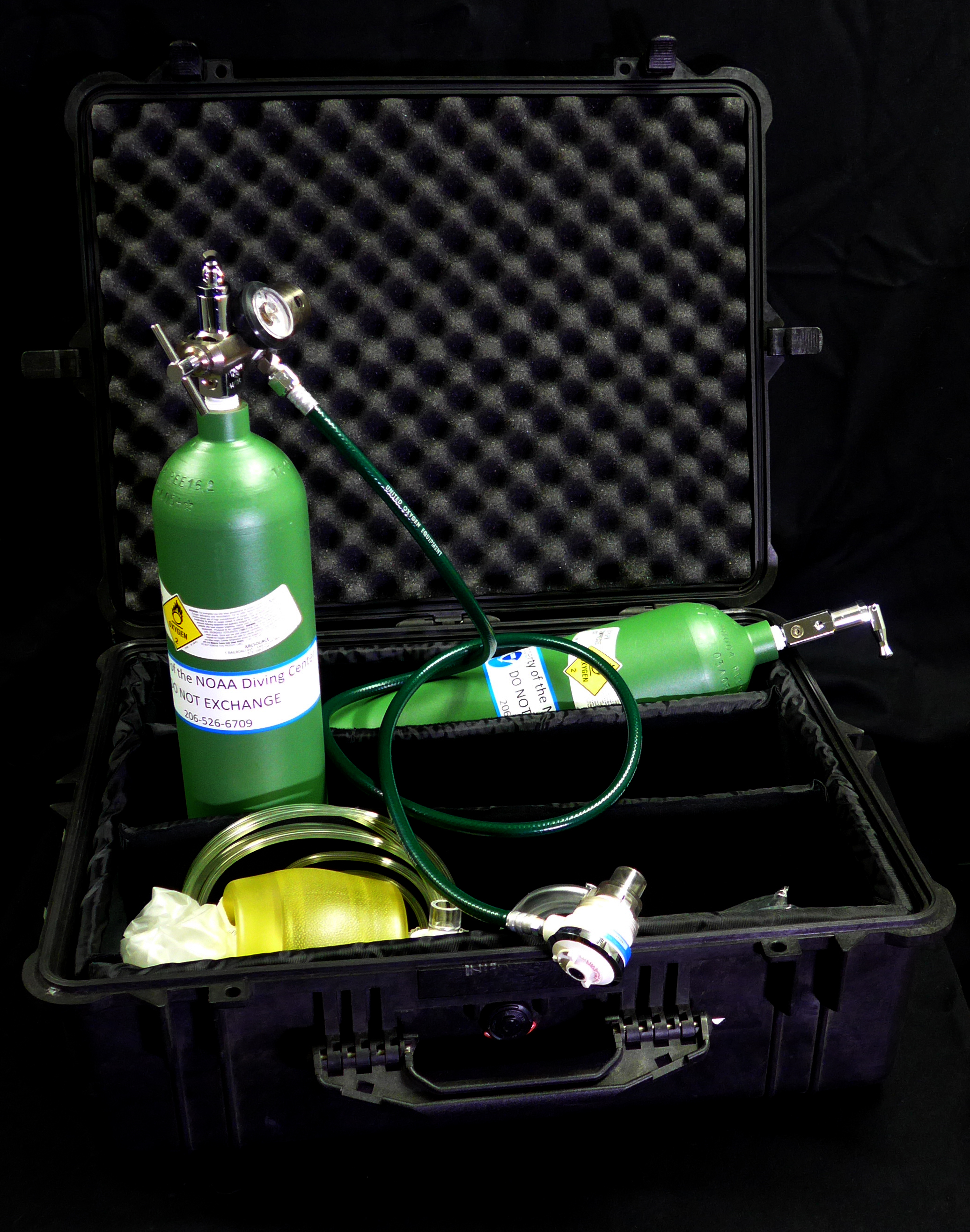 An opened oxygen kit case containing two oxygen bottles and other items
