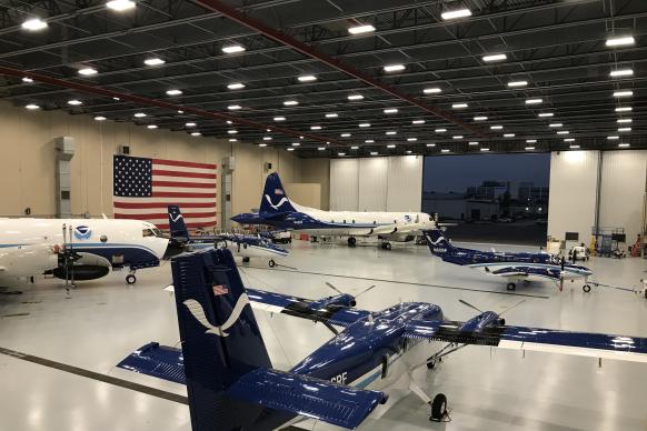 NOAA aircraft in a hangar with the U.S. flag in the background