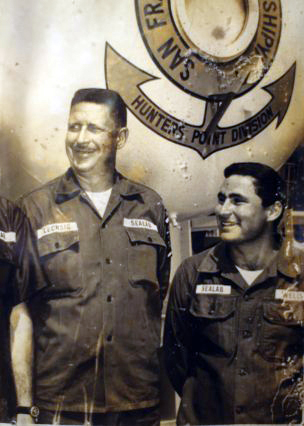 Two officers posing in front of a hyperbaric chamber