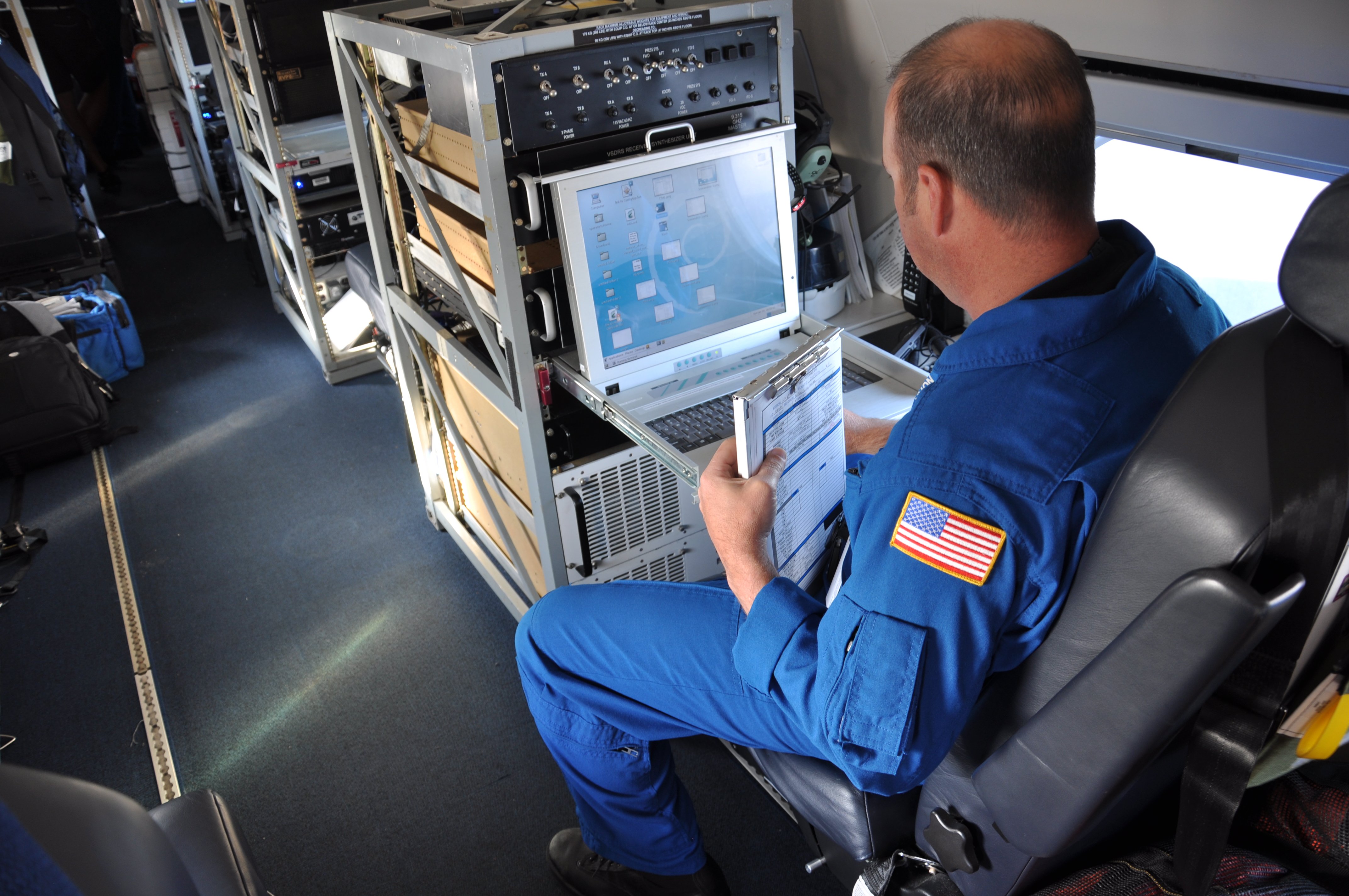 NOAA Aircraft Lead Electronics Technician sits in front of laptop.