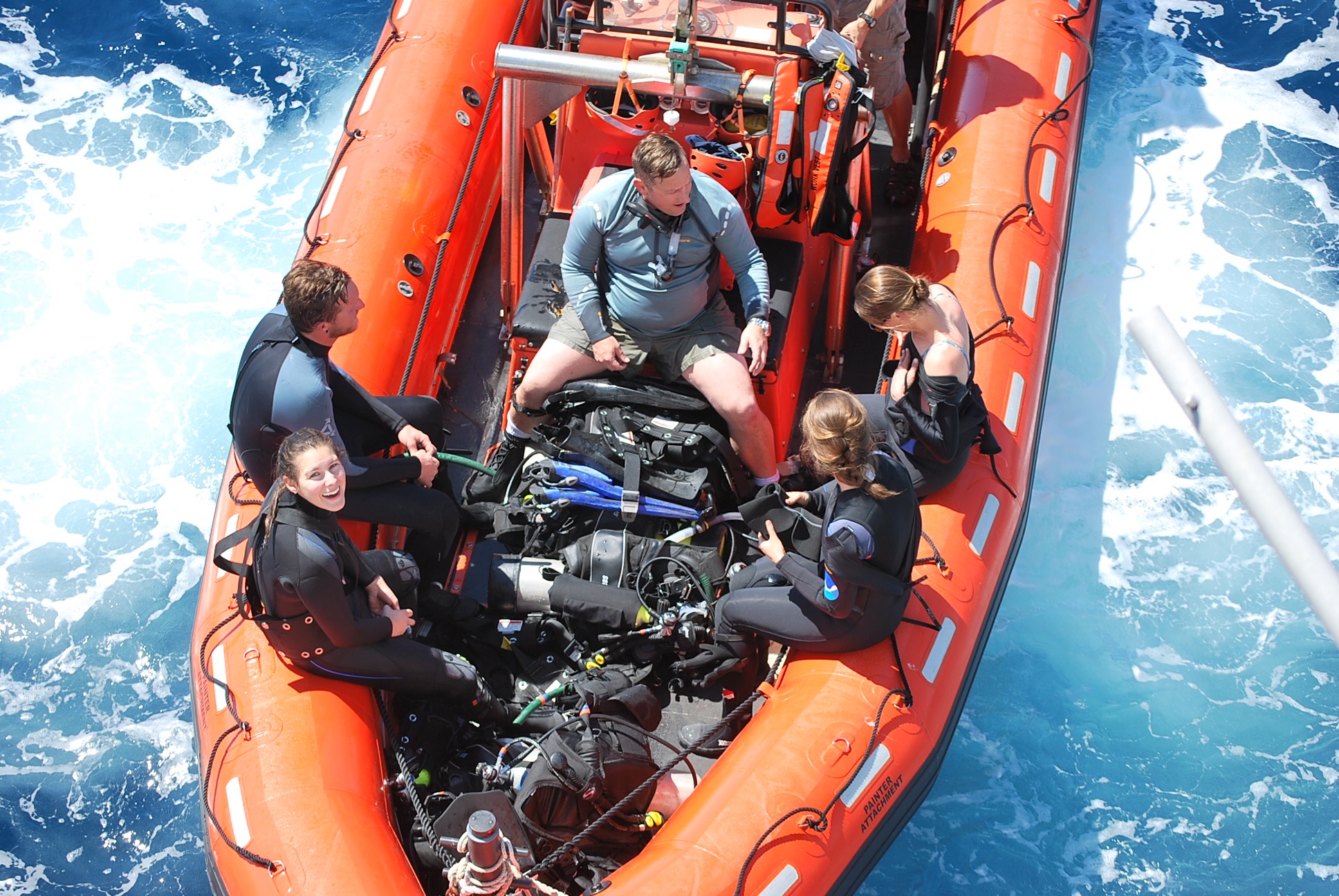 Five divers sit inside an inflatable boat in preparation for their dive