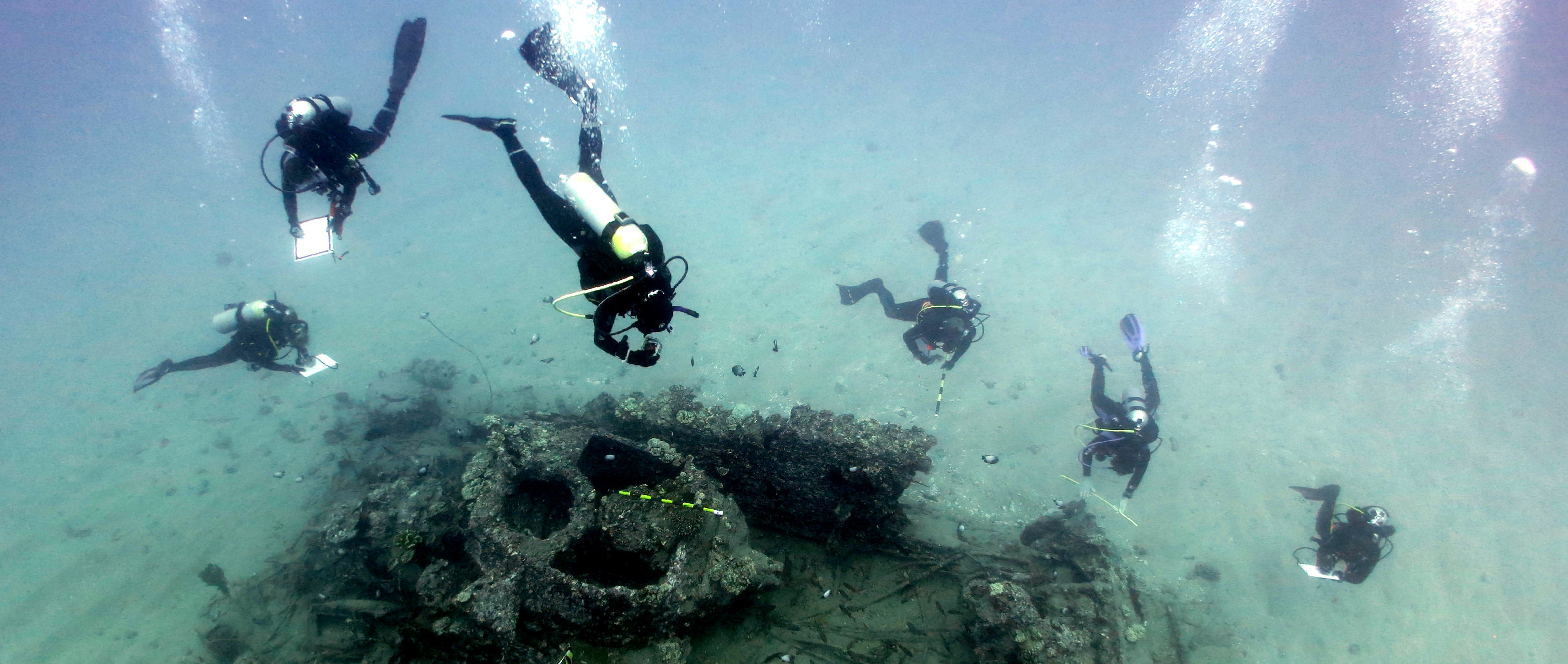A group of divers map the remains of a sunken amphibious vessel.