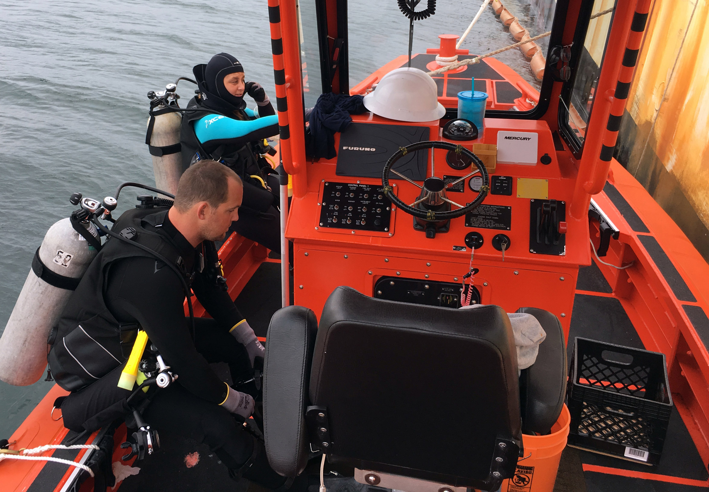 Divers on a boat getting geared up to dive