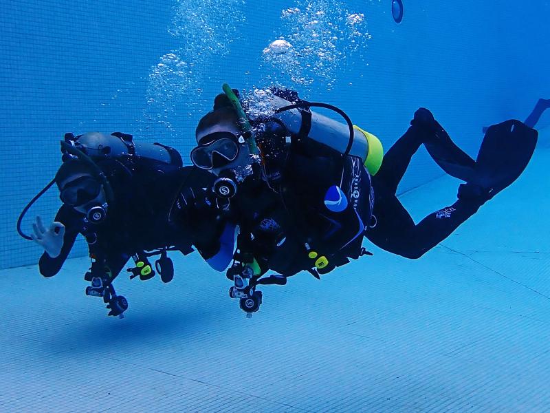 A pair of NOAA scuba dives under water in a swimming pool