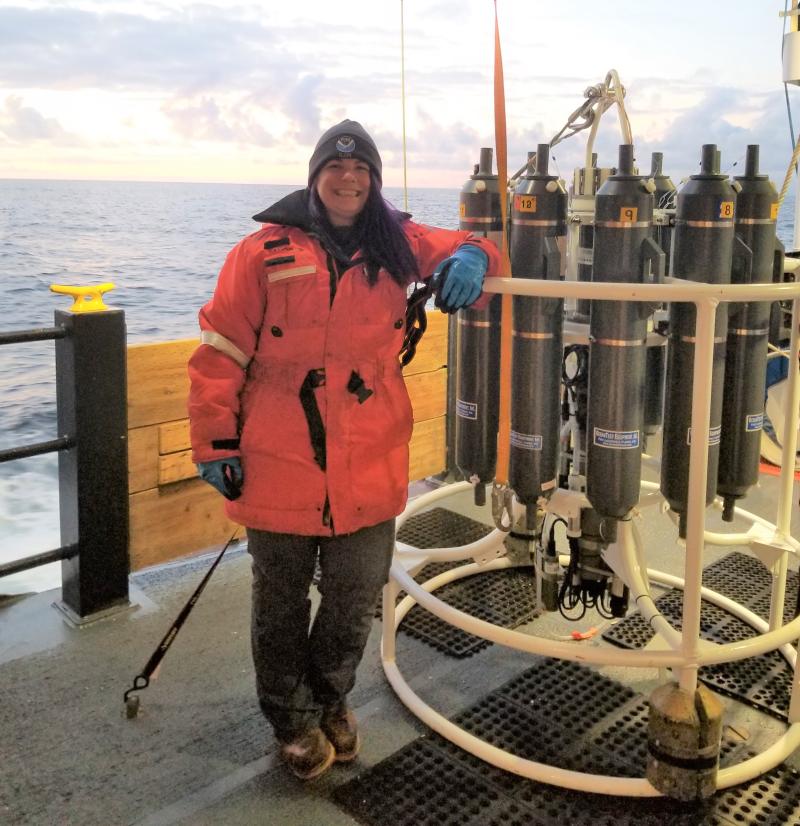 A female senior survey technician on aboard a ship with a water sampling instrument