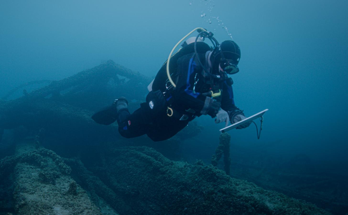 A NOAA scuba diver studies a shipwreck