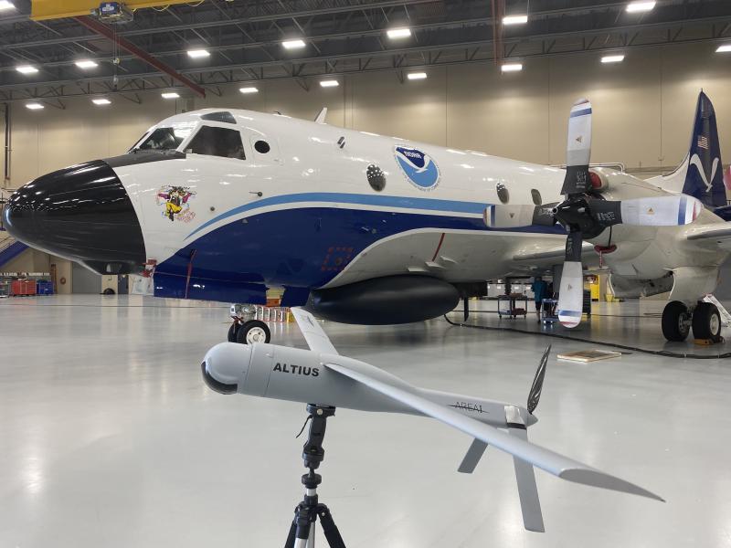 NOAA WP-3D Orion aircraft with model of a small gray uncrewed aircraft