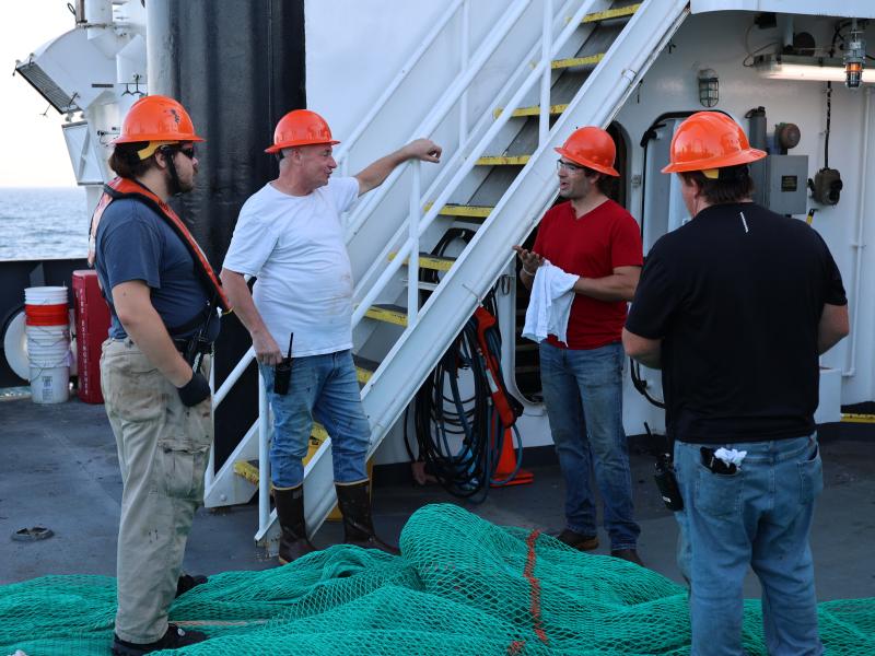 A group of crew members meet on the deck of a NOAA ship