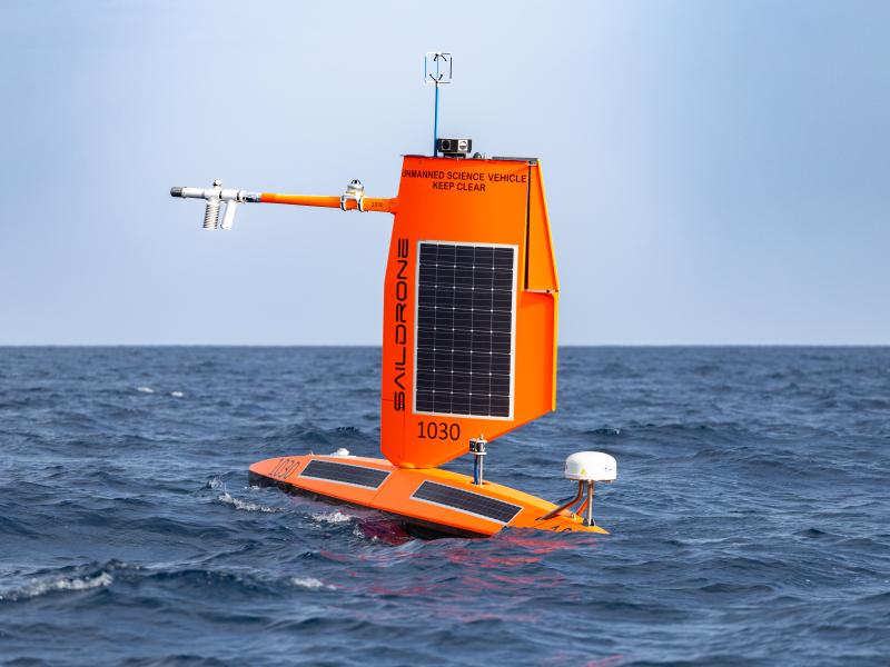 An orange uncrewed surface vehicle sits at the surface of the ocean