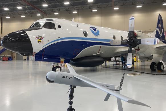 NOAA WP-3D Orion aircraft with model of a small gray uncrewed aircraft