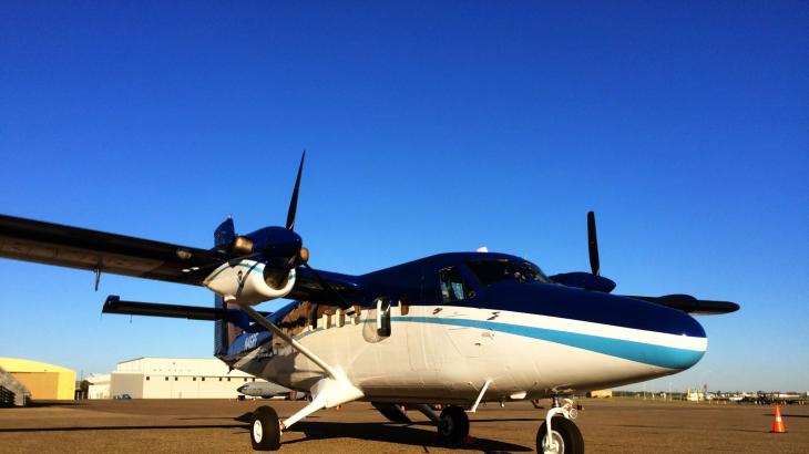 A twin-engine NOAA Twin Otter airplane parked on the ground at an aiport