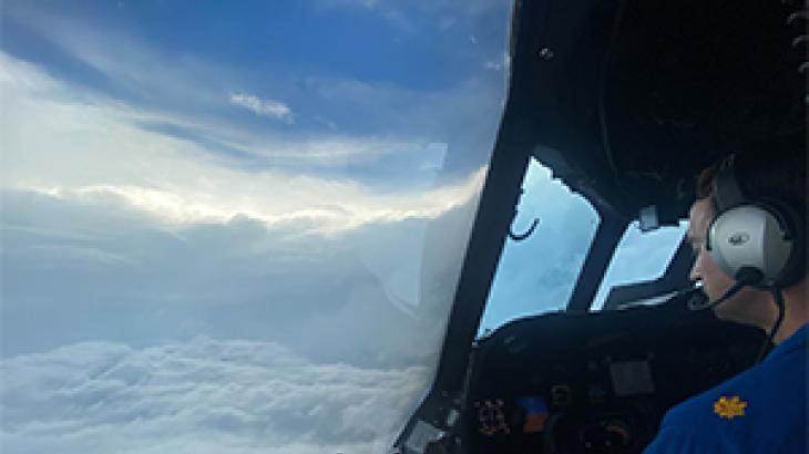 The eye of a hurricane and a pilot as seen from the flight station of a NOAA aircraft