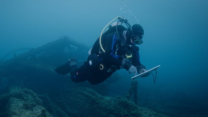 A NOAA scuba diver studies a shipwreck