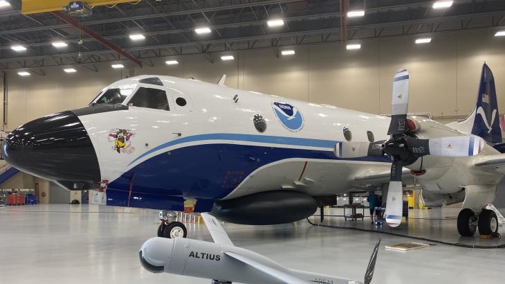NOAA WP-3D Orion aircraft with model of a small gray uncrewed aircraft