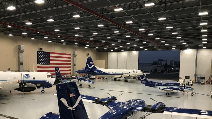 NOAA aircraft in a hangar with the U.S. flag in the background