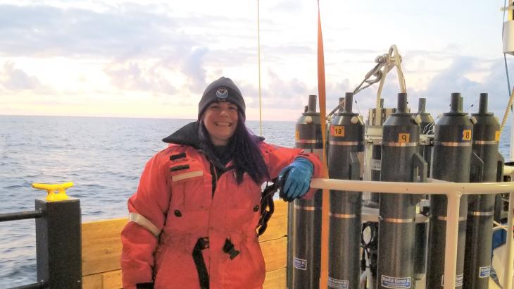 A female senior survey technician on aboard a ship with a water sampling instrument