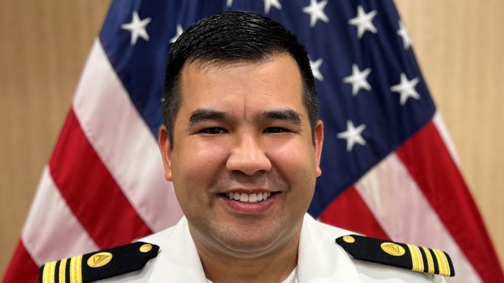 Lieutenant Commander Andrew Reynaga posed in front of the American flag.
