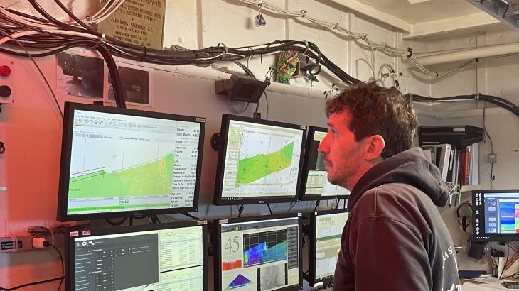A survey technician monitors data collection aboard a NOAA ship