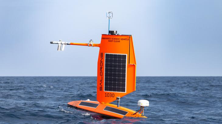 An orange uncrewed surface vehicle sits at the surface of the ocean