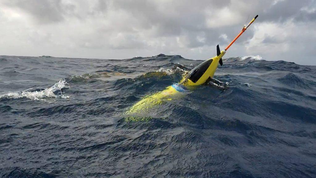 A yellow glider bobs at the surface of the ocean.