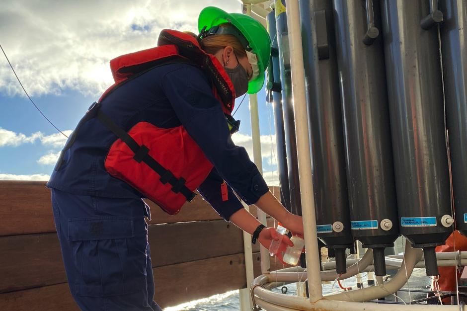 Lt. j.g. Edmonds is on the left collecting water samples from a CTD device on the right.