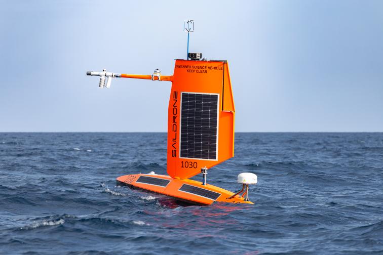 An orange uncrewed surface vehicle sits at the surface of the ocean